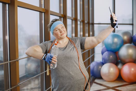 A smiling woman in a gym taking a selfie during her workout, showcasing a positive and active lifestyle.