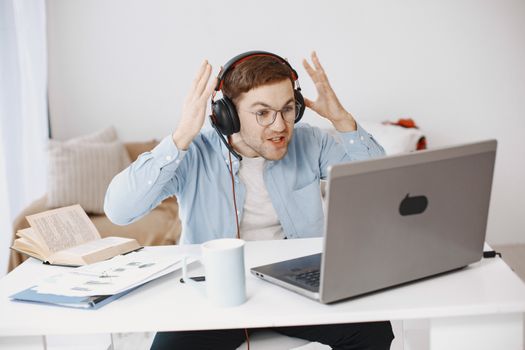 Man expressing frustration with remote work at home desk setup.