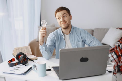 Man Sitting by Desk with Laptop and Lightbulb