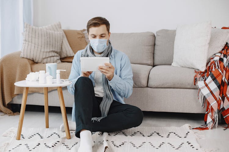 Sick Man Sitting With Mask In Living Room