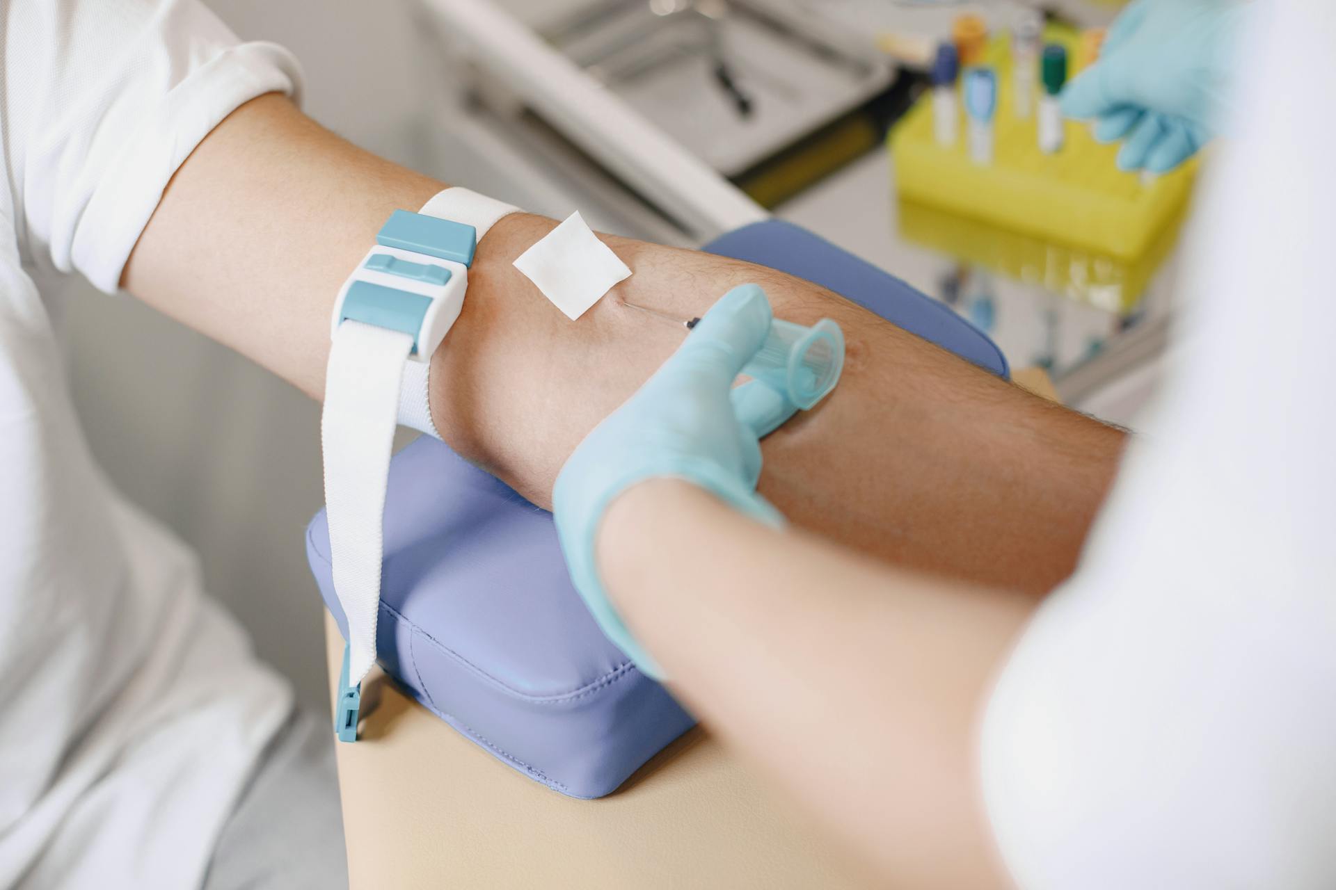 Close-up of a medical professional drawing blood from a patient's arm in a clinical setting.