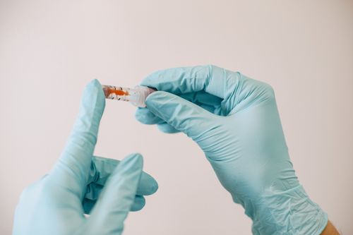 Free Close-up image of gloved hands holding a syringe in a sterile environment. Stock Photo