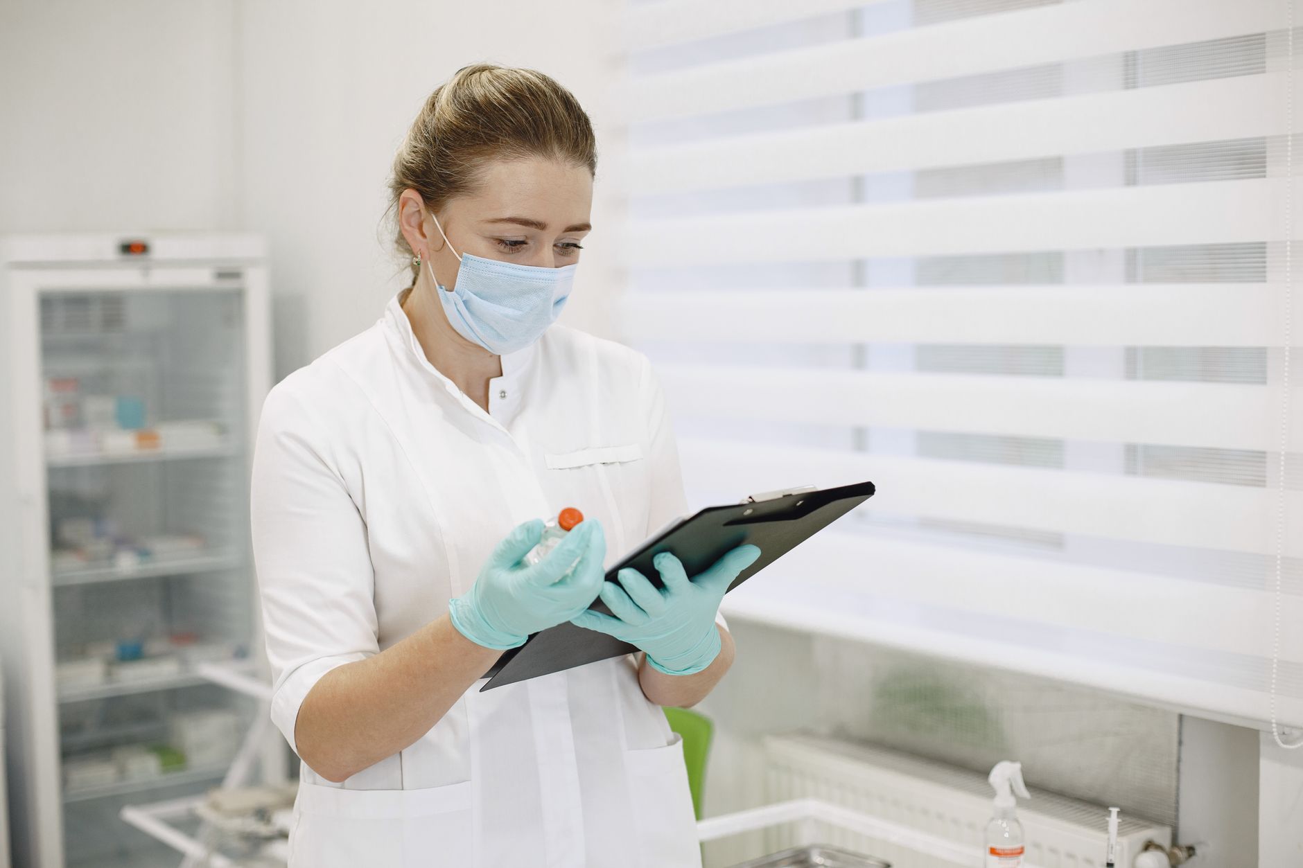 Medical professional in a clinic reviewing patient records while wearing protective gear.