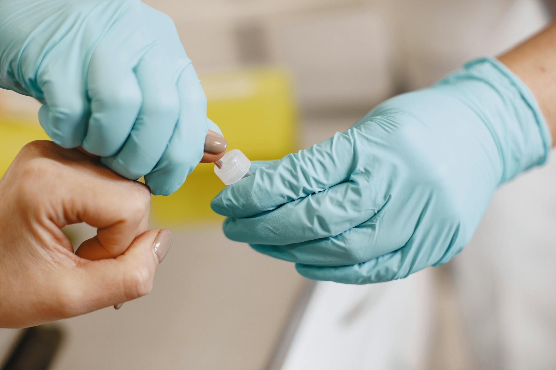 Close-up of a healthcare worker performing a blood test using sterile gloves.