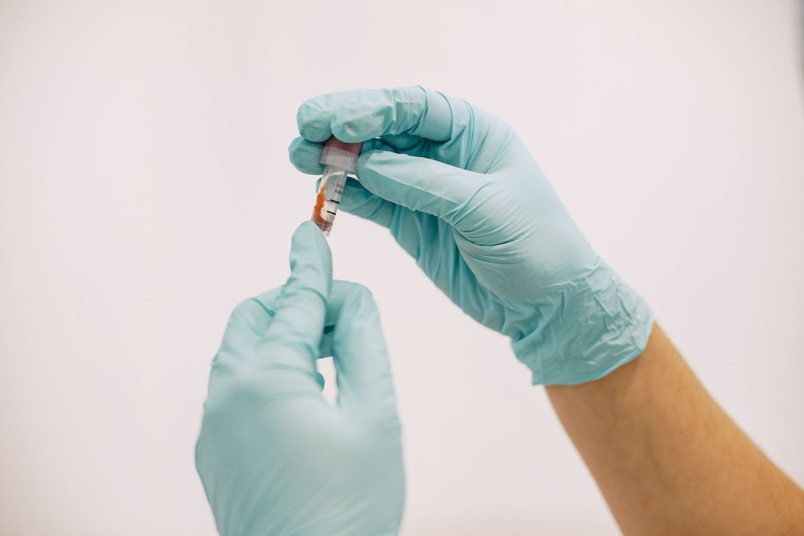 Gloved laboratory professional holding a testing sample