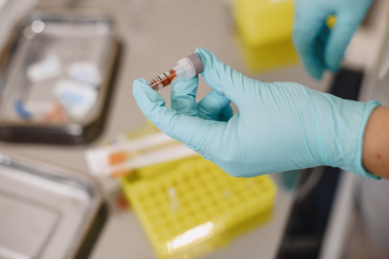 A gloved hand holding a small sample vial in a laboratory — photo by Gustavo Fring on Pexels
