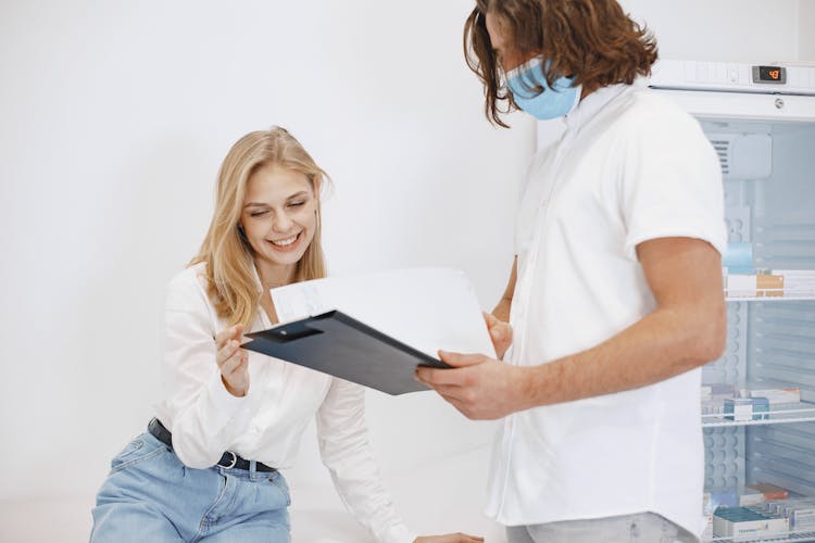 Woman In A Medical Examination Room With Her Doctor Looking At The Chart 