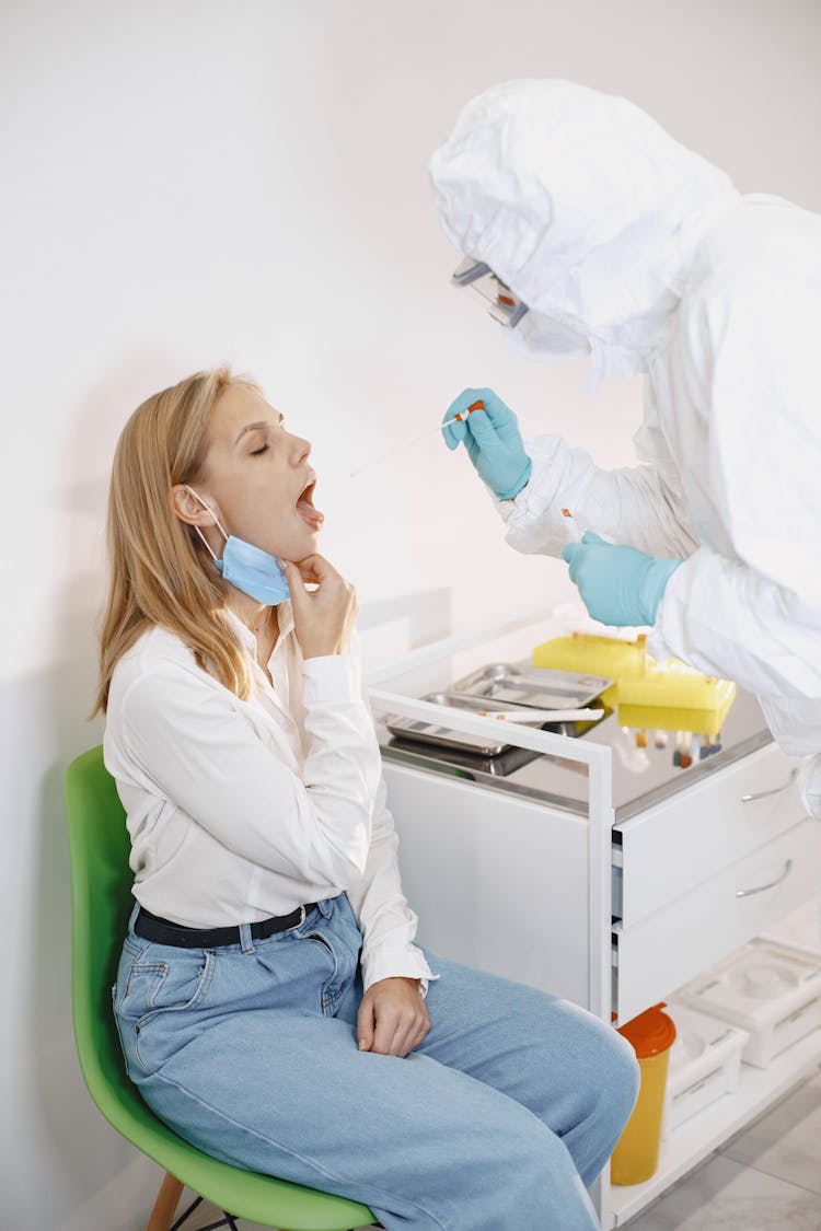 A Woman With Her Mouth Open Getting A Swab Test