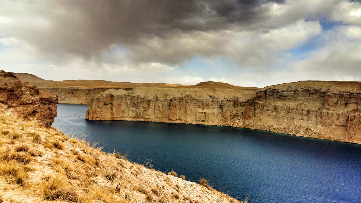 Body of Water Surrounded by Rock Formation Under Cloudy Sky