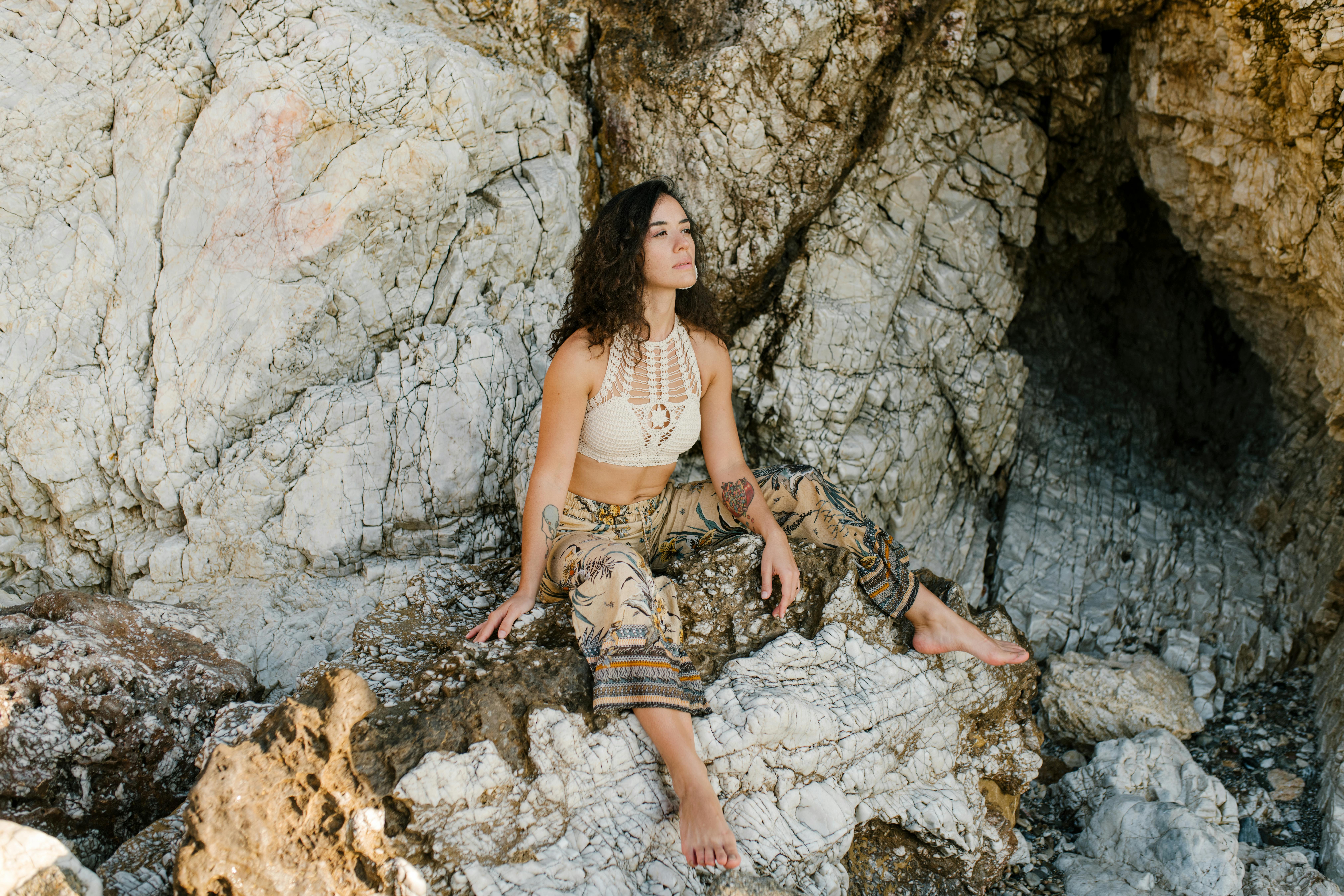 young woman in summer outfit relaxing on stones in mountain terrain