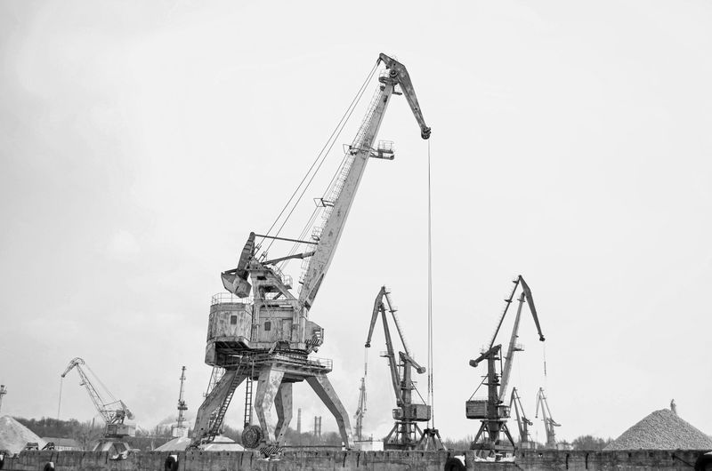 Black and white photo of industrial cranes at a construction site, showcasing heavy equipment