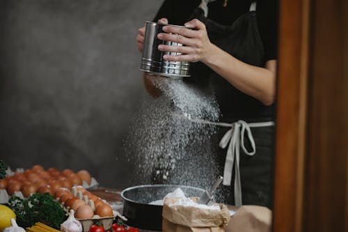 Anonymous chef cooking pasta on table near ingredients