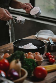 Crop anonymous chef in apron preparing ingredients for adding to flour in baking form at kitchen