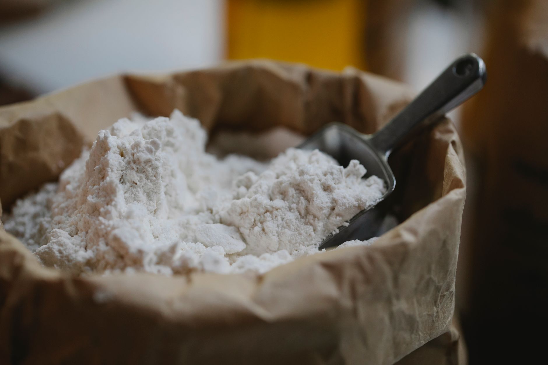 High angle of wheat flour with metal scoop prepared for pastry and cooking process