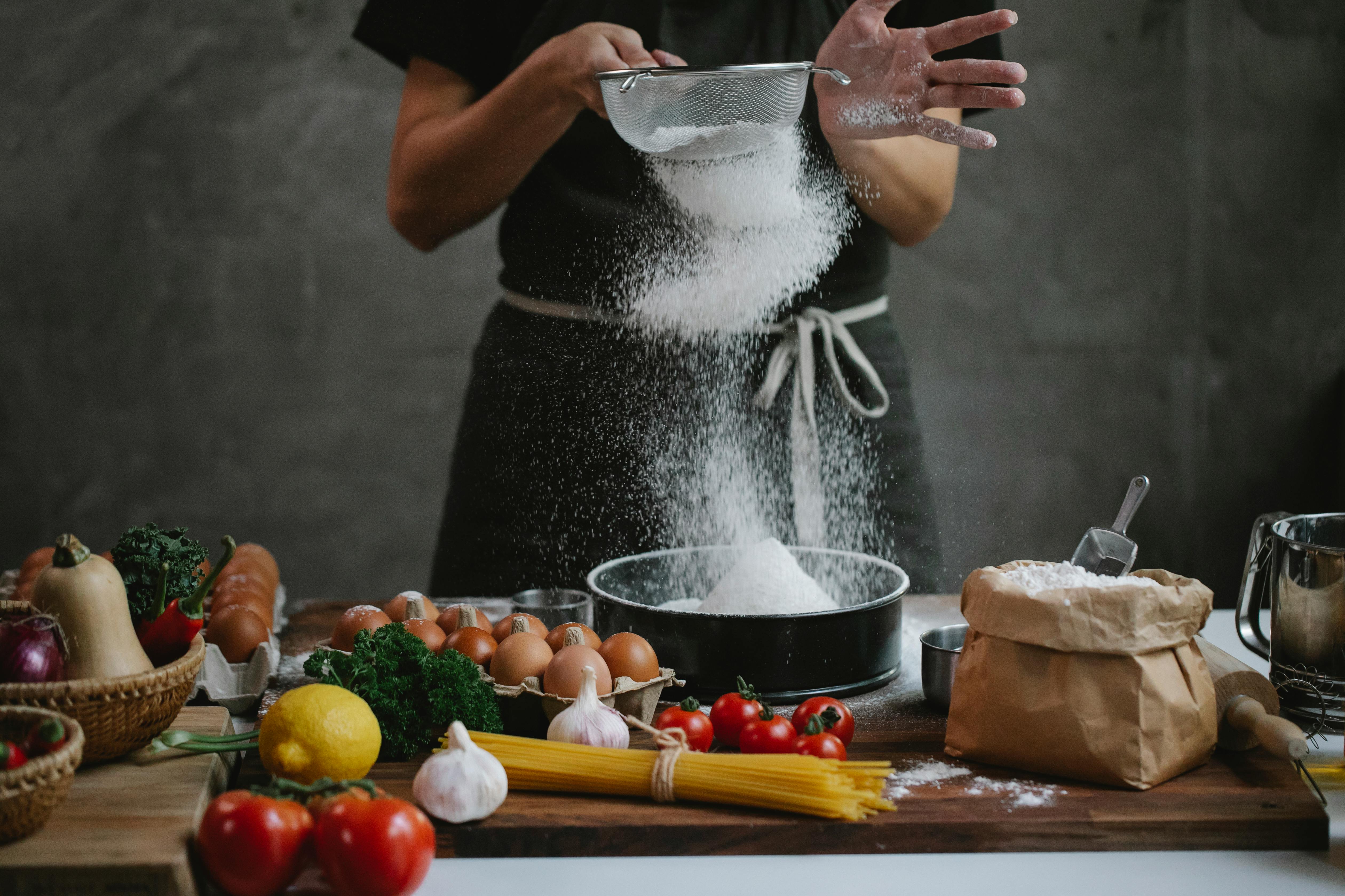 cook adding flour into baking form while preparing meal