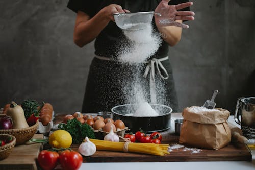 Free Cook adding flour into baking form while preparing meal Stock Photo