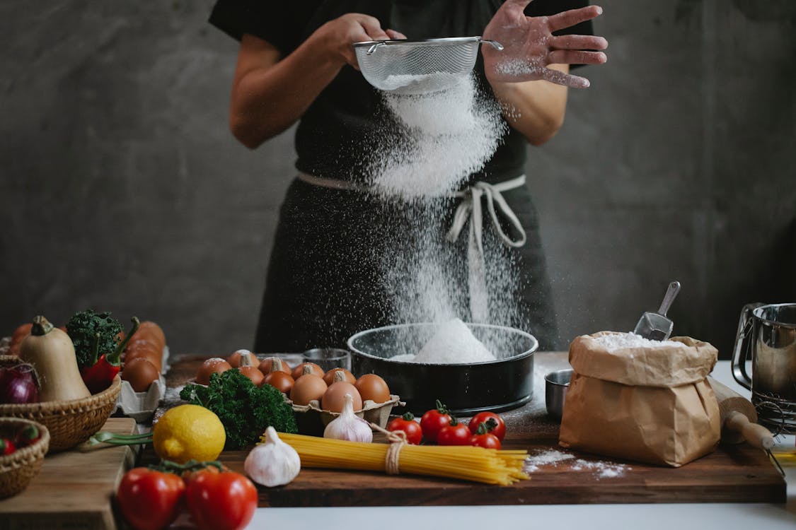 Cook adding flour into baking form while preparing meal