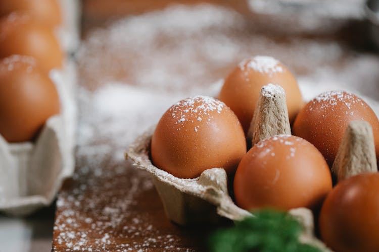 Eggs In Carton Container On Table With Flour