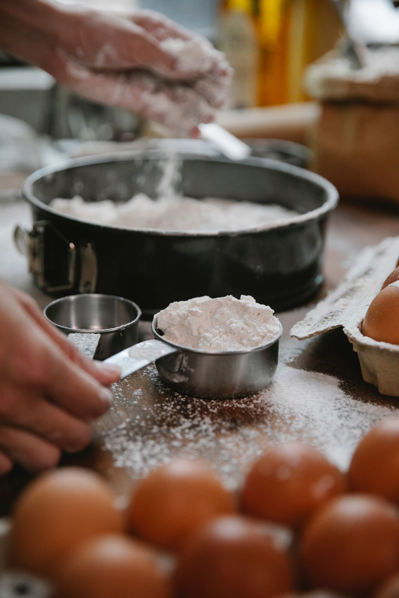 Flour, eggs and baking tools being prepared beside a baking pan