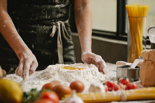 Cook preparing dough with flour and eggs