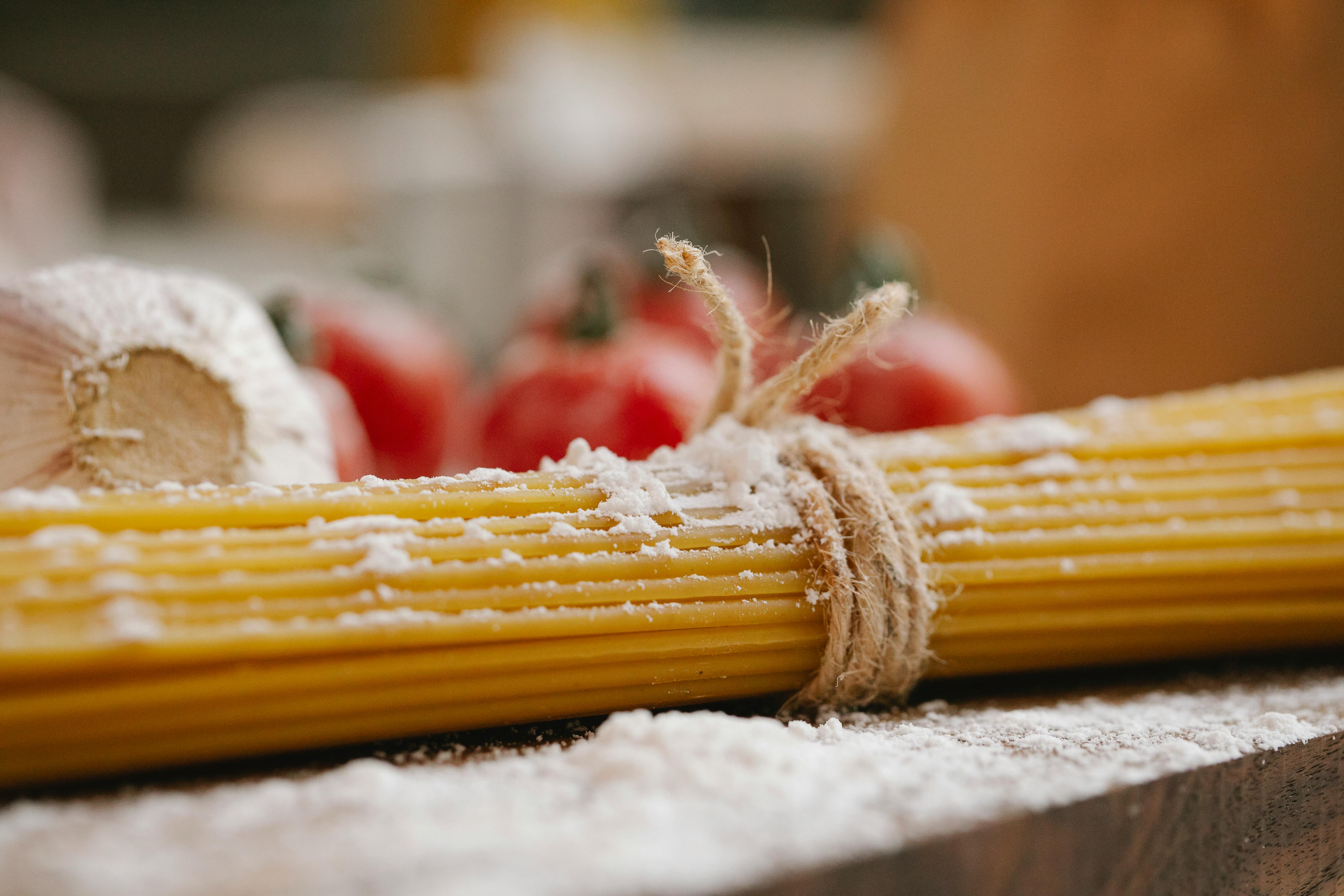 Closeup of ingredients for cooking Italian dish consisting of spaghetti tomatoes and garlic with flour