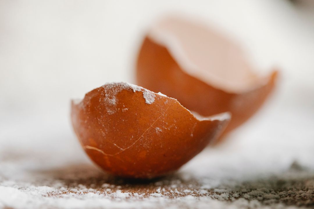 Cooking Classes in Ahmedabad for Beginners: What to Expect, What to Learn, and Where to Start (2026) 1 Close-up of a broken eggshell resting on a flour-dusted baking surface, representing essential pastry and baking ingredients.