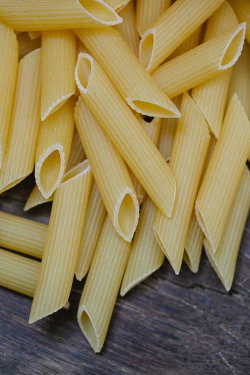 Free From above pile of uncooked pasta scattered on wooden table for cooking preparation Stock Photo