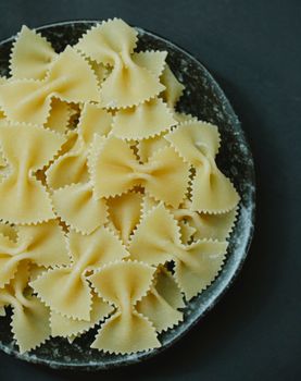 From above of traditional Italian raw dried farfalle pasta in bowl on table