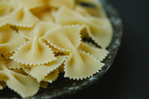Free High angle of raw dried traditional Italian farfalle pasta in bowl on black background Stock Photo