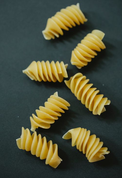 Free From above of few raw twirls of traditional Italian fusilli pasta on black background Stock Photo