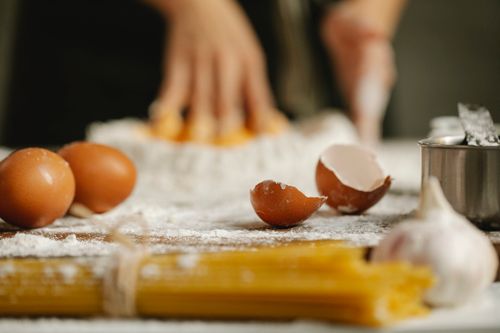 Free Table for cooking in kitchen with eggs eggshells spaghetti and garlic on blurred background Stock Photo