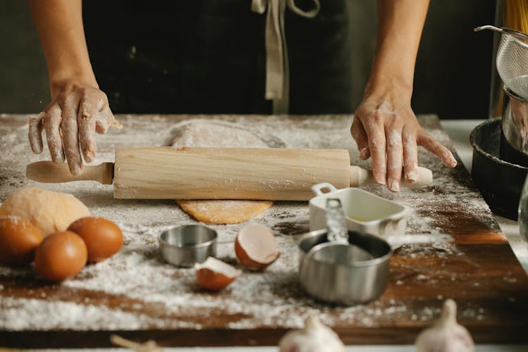 Chef Rolling Dough On Table In Kitchen