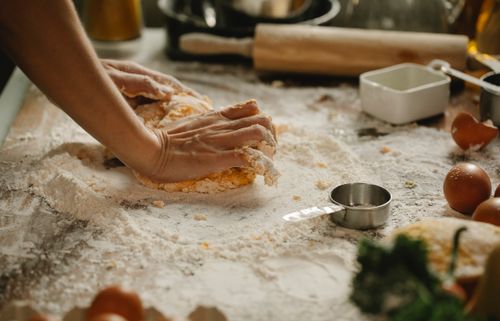 Free Unrecognizable woman kneading egg dough on table with flour and cooking ingredients in kitchen Stock Photo