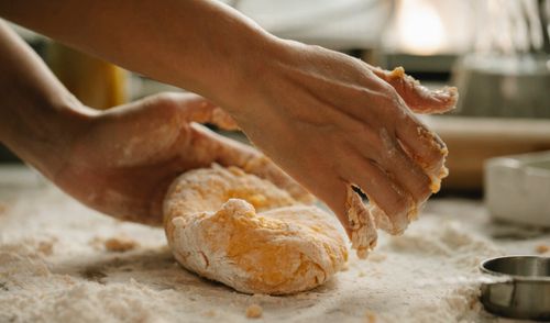 Free Unrecognizable woman kneading fresh dough on wooden table with flour while preparing food in kitchen Stock Photo
