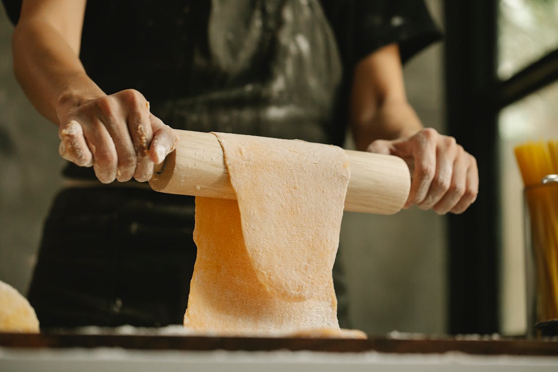Free Chef stretching dough on rolling pin for making pasta Stock Photo