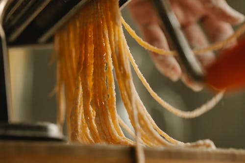 Crop cook using pasta machine while preparing spaghetti