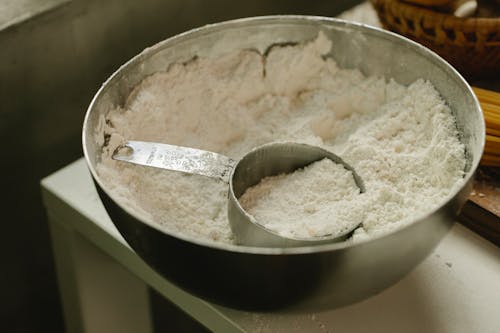 Bowl with flour and measuring cup in kitchen