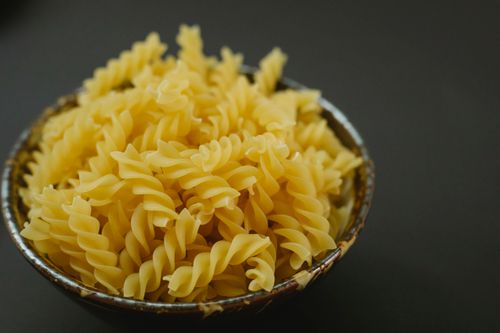 Free Heap of uncooked spiral shaped fusilli pasta served in plate and placed on black background in kitchen on blurred background Stock Photo