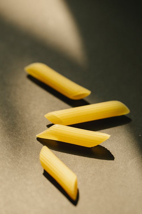 Raw penne pasta scattered on black table