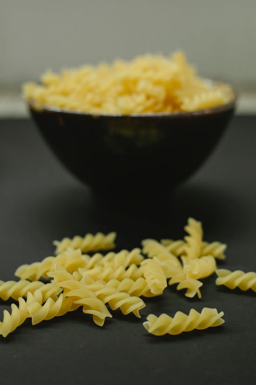 Free Bowl with raw pasta on table against bowl Stock Photo