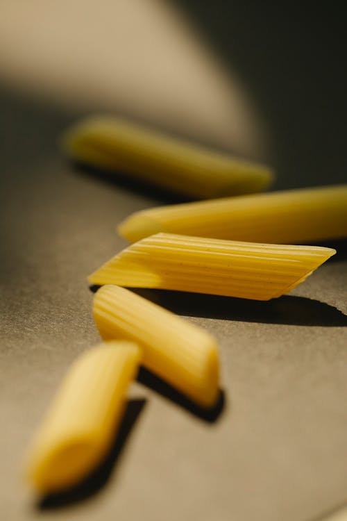 Raw penne pasta on black surface