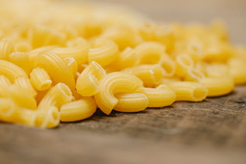 Closeup of pile of fresh uncooked curvi rigati pasta scattered on wooden table in kitchen