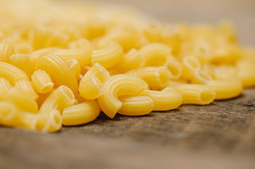 Free Closeup of pile of fresh uncooked curvi rigati pasta scattered on wooden table in kitchen Stock Photo