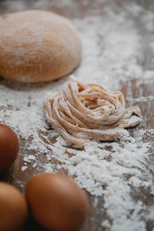 Dough and eggs on floury table during pasta preparation