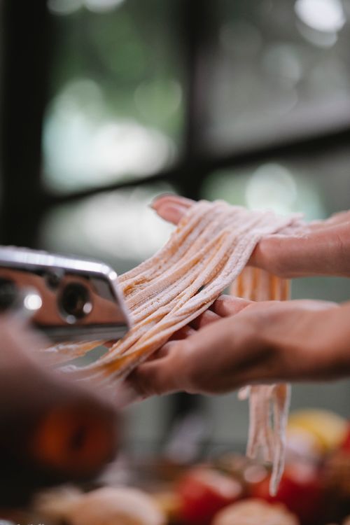 Free Crop anonymous female cooking macaroni from dough and pasta maker on blurred background Stock Photo
