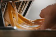 Person cutting noodle with pasta machine