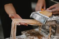 People cutting spaghetti with pasta machine