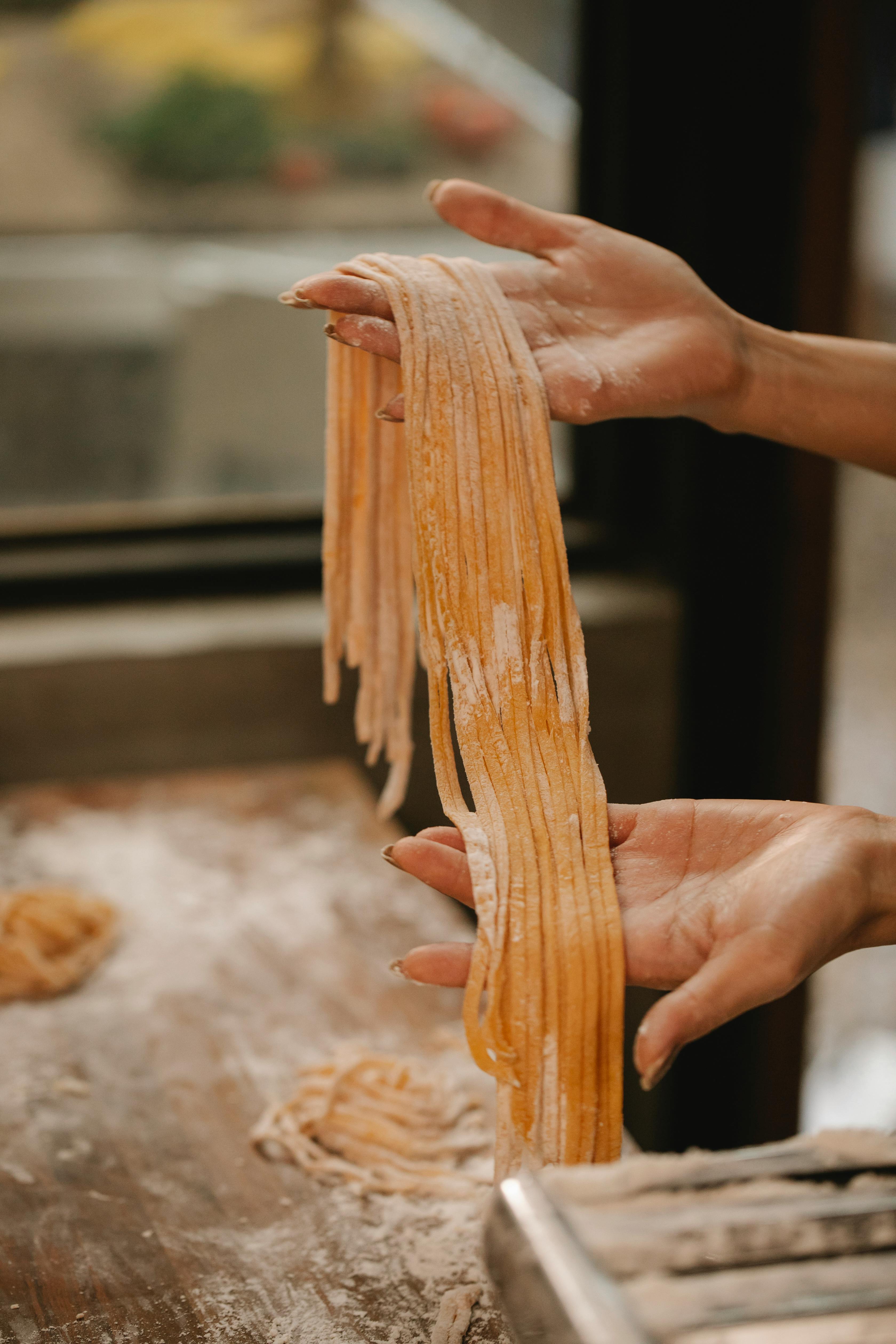 crop faceless chef demonstrating tagliatelle pasta in kitchen