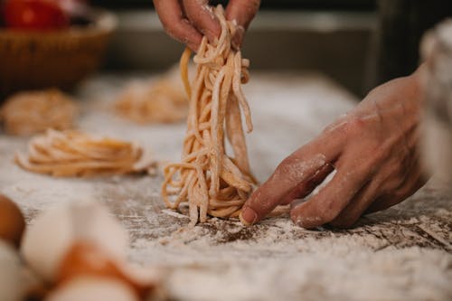 Crop faceless chef preparing pasta nests on table