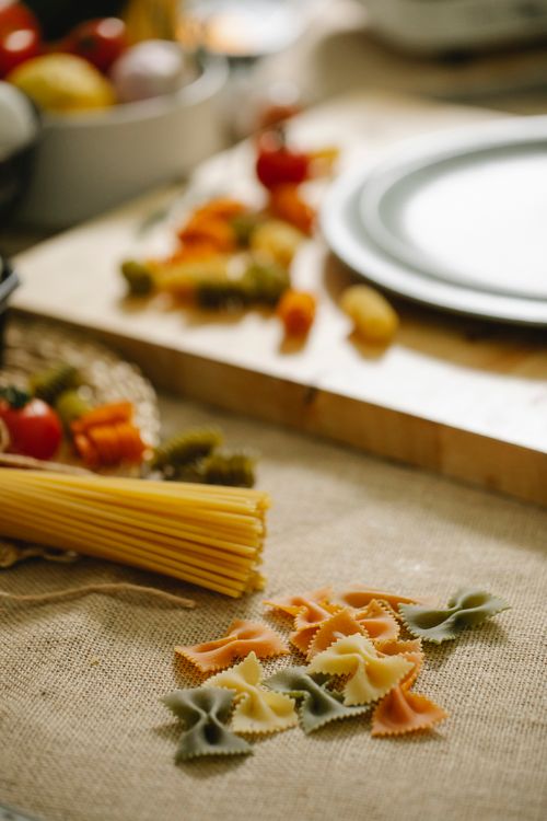 Free Composition of raw assorted pasta including spaghetti and multicolored farfalle arranged on table in light kitchen Stock Photo